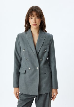 Blazer gris de doble botonadura con botones plateados, solapas muestradas, dos bolsillos frontales y un ajuste entallado. Textura suave, diseño estructurado.