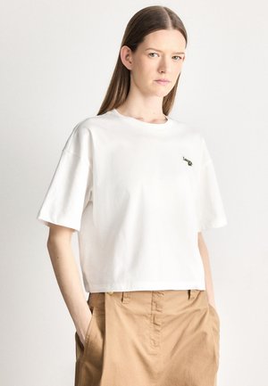 T-shirt bianca a maniche corte con vestibilità rilassata e scollatura rotonda. Presenta un piccolo logo verde sull'area sinistra del petto. Realizzata in cotone.