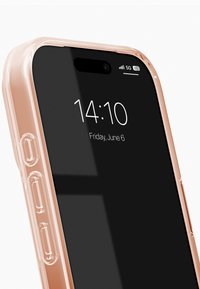 Przezroczyste etui na telefon w miękkim brzoskwiniowym odcieniu, lekko prześwitujące, dopasowane do czarnego smartfona, na ekranie którego wyświetlany jest czas i data.