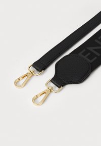 Sangle ajustable en faux cuir noir avec des accessoires en métal doré, dotée de deux attaches à clip et d'un design texturé, adaptée aux sacs ou aux accessoires.