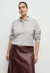 Svijetlosivi džemper s teksturom, ovratnikom i gumbima, upareni s uskom suknjom od umjetne kože u boji tamnocrvene.