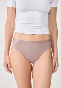 Jasnofioletowa bielizna damska o gładkiej fakturze i cienkiej, błyszczącej, elastycznej talii. Prosty design, bez dodatkowych wzorów czy akcentów.