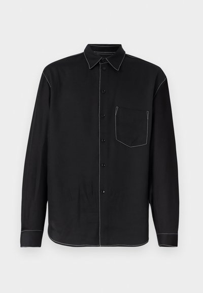 Μαύρο πουκάμισο με μακριά μανίκια και κουμπιά, με λευκή αντίθετη ραφή, τσέπη στο στήθος μπροστά και μυτερό γιακά, απεικονισμένο σε απλό φόντο.