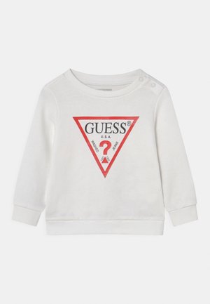 Biały niemowlęcy shirt z długim rękawem, z trójkątnym logo z czerwonym obramowaniem z napisem "GUESS U.S.A." oraz dwoma zatrzaskami na jednym ramieniu.