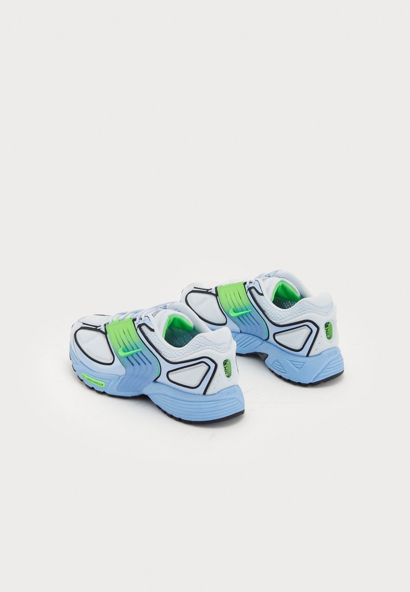 Zapatillas deportivas blancas con acentos en azul y verde, parte superior de malla y sintético, puntera redondeada, suela gruesa y amortiguación de aire visible.