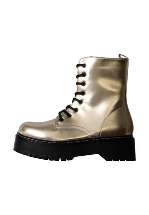 Botte de combat dorée brillante avec semelle épaisse noire à crampons et lacets noirs, vue de côté sur fond blanc.