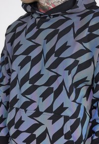 Felpa con cappuccio nera con un motivo geometrico iridescente. Presenta una tasca frontale e un design a vestibilità comoda.