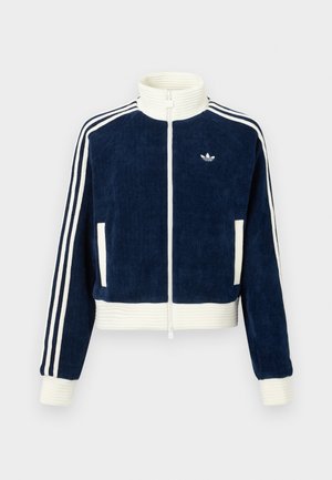 Jūras spēku tumši zils korduroja zip-up džemperis ar baltu ribotu apkakli un aprocēm. Uz piedurknēm trīs baltas svītras un mazs logo uz krūšu daļas. Divas priekšējās kabatas.