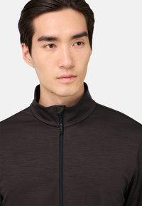 Tmavě šedá zipová bunda s vysokým límcem, s jemnou texturou a předním zipem, navržená pro komfort a pohyblivost.