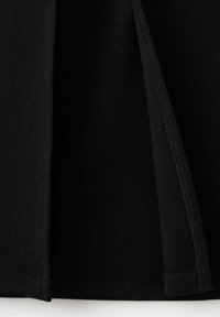 Gros plan sur un tissu noir montrant une fente latérale avec des coutures visibles et des bords repliés à l'ourlet.