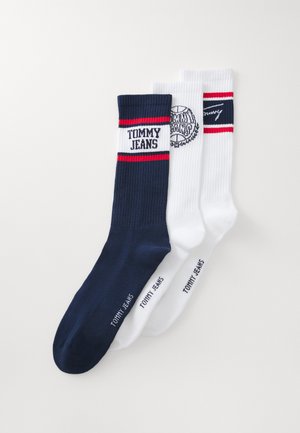 Kolme paria ribbikudumisega sokke tumedast mereväe sinisest, valgest ja punaste triipudega. "TOMMY JEANS" logo on kuvatud mereväe siniste sokkide peal.