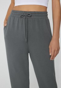 Graue Jogginghosen aus weichem Material, mit einem elastischen Bund und Kordelzug, seitlichen Taschen und einer lockeren Passform.