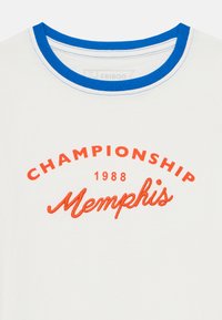 Valge T-särk sinise ribaga kaelusega, millel on oranž tikand: "CHAMPIONSHIP 1988 Memphis." Sile puuvillane kangas, hüva disain.