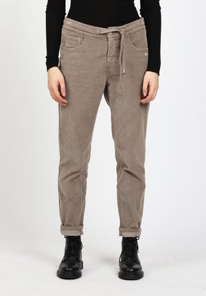 Beige corduroy pants with drawstring waist and rolled cuffs worn with black lace-up boots and a black long-sleeve top.