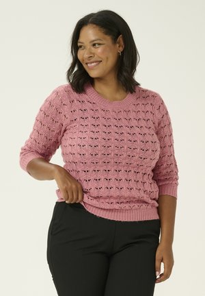 Pink knitted sweater featuring a textured, open-weave pattern, crew neckline, and three-quarter sleeves, paired with black trousers.