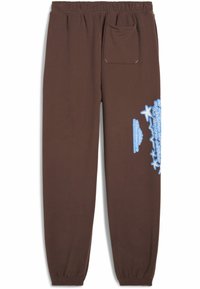 Hnedé tepláky vyrobené z mäkkého materiálu, s dizajnom sťahovacieho členka, elastickým pásom a modrým grafickým textom na boku.