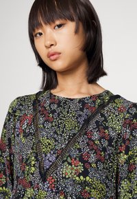 Vestido com padrão floral em preto, apresentando flores multicoloridas, decote em V e delicadas rendas nas bordas. Tecido texturizado.