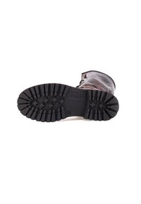 Brązowy skórzany but z teksturowaną cholewką, z wytrzymałą czarną gumową podeszwą i wyraźnym wzorem bieżnika dla lepszej przyczepności.