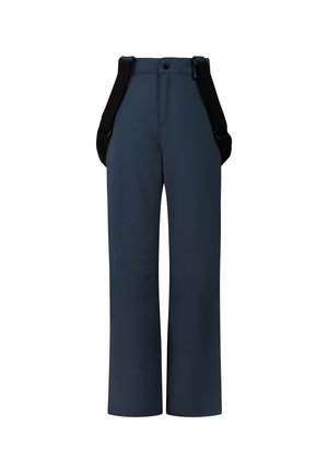 Enfant portant une polaire beige, un pantalon de neige bleu marine avec des bretelles, des bottes noires et un bonnet gris, debout les mains dans les poches sur un fond uni.