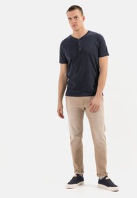 Marineblå kortærmet henley skjorte med tre knapper, parret med lysebeige slim-fit bukser og marineblå sneakers, minimal stofstruktur.