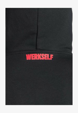 Sort sweatshirt med ribbet struktur, hvor ordet "WERKSELF" står med fed røde bogstaver på den nederste front.