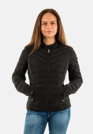 Zwarte gewatteerde jas met een hoge kraag en ritssluiting aan de voorkant, met een patroontextuur en zijzakken, gedragen over blauwe jeans.