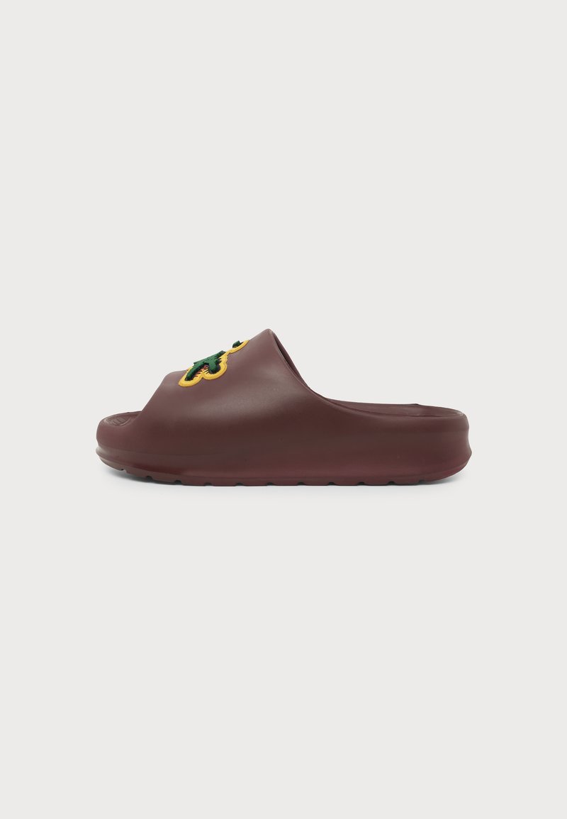 Καφέ σανδάλι τύπου slip-on με παχιά σόλα και πράσινο και κίτρινο κεντητό σχέδιο στο επάνω μέρος, εμφανίζεται σε πλαϊνό προφίλ.