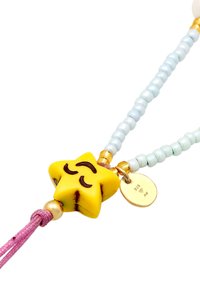 Gelbes Sternchen mit Lächel-Design, umgeben von hellblauen und rosa Perlen, goldenen Akzenten und einem kleinen Metallanhänger mit der Aufschrift "925".