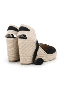 Wedges de esparto en negro y beige con suela de yute, talón abierto y una tira decorativa negra en la parte trasera. Parte superior de tela texturizada.