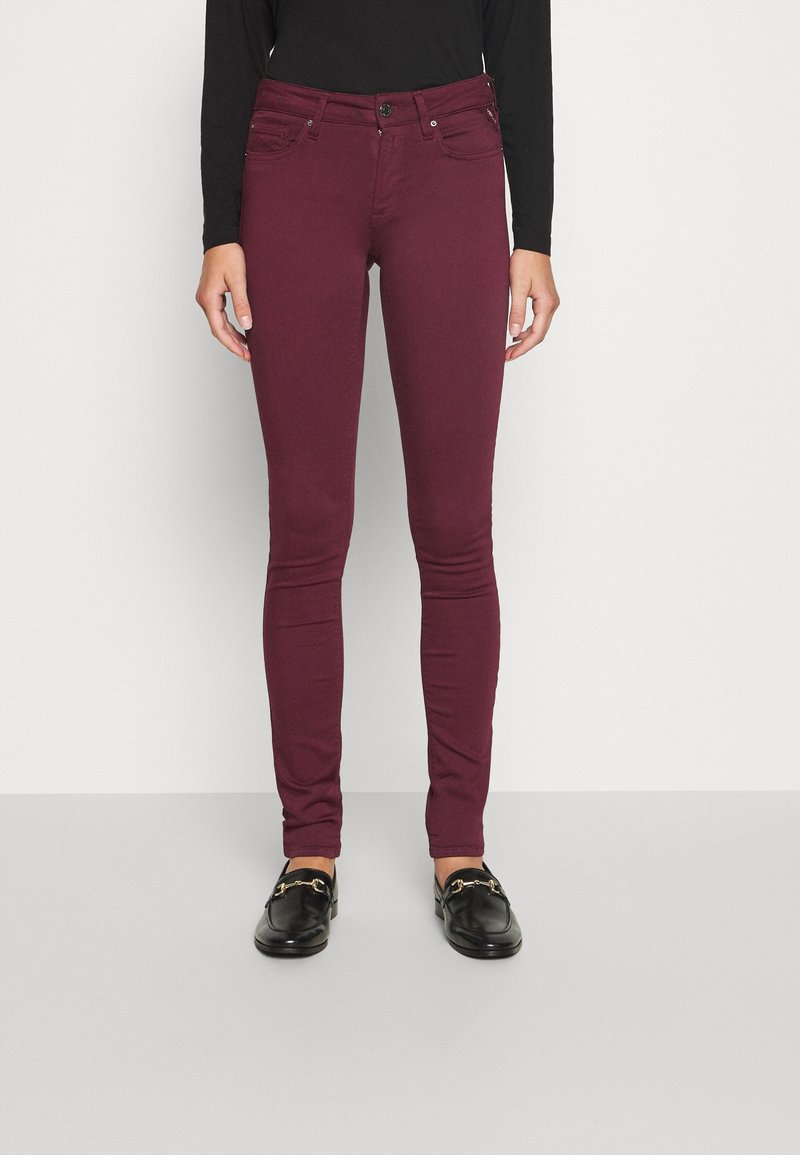 Jeans skinny burdeos con cierre de botones, dos bolsillos frontales y un diseño ajustado. Fabricados con una tela suave y elástica para mayor comodidad.