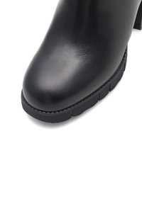 Czarne skórzane botki za kostkę z okrągłym noskiem i teksturowaną czarną gumową podeszwą. Charakteryzują się eleganckim wykończeniem i subtelnym detalem w postaci szwów.