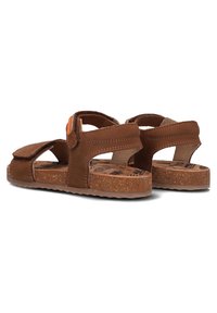 Brown sandal with an open toe design, suede material, Velcro strap, cork footbed, and textured rubber outsole.