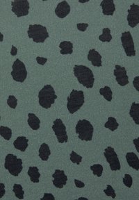 Textilní látka s zeleným pozadím a rozmístěnými černými leopardími skvrnami různých tvarů a velikostí, hladká textura.