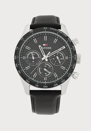 Montre-bracelet pour homme avec bracelet en cuir noir, cadran noir, trois sous-cadrans, aiguilles argentées, lunette tachymètre et logo Tommy Hilfiger.