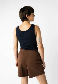 Marineblaue Tanktop mit rundem Ausschnitt kombiniert mit Shorts mit braunem Gummibund. Sieht sichtbare Nähte und einen lockeren Schnitt vor. Minimalistisches Design.