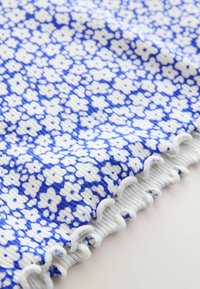 Kék-fehér mintás textil apró virágmintákkal, hullámos széllel. Könnyű és puha anyag.