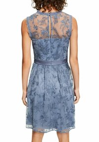 Vestido azul bordado con una espalda transparente y patrones florales. Terminado con un cinturón de tela. Presenta un cierre de ojal y un escote con volantes.