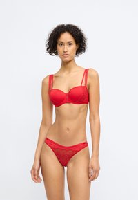 Set de lenjerie roșie care include un sutien cu pernuțe, detaliat cu dantelă și bretele ajustabile, asortat cu un thong care prezintă detalii din dantelă florală.