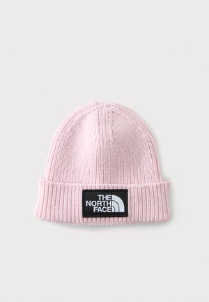 Bonnet tricoté rose clair avec bord replié et patch rectangulaire noir affichant le logo "The North Face" en lettres blanches.