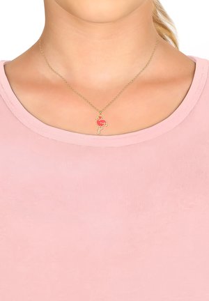 Gul kæderez med en flamingo vedhæng med pink og røde accenter. Båret af en person med rund halsudskæring i en lys pink top.