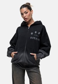 Felpa nera con zip e sfumatura grigia, dotata di testo grafico sul petto, ampie tasche frontali e polsini a coste.