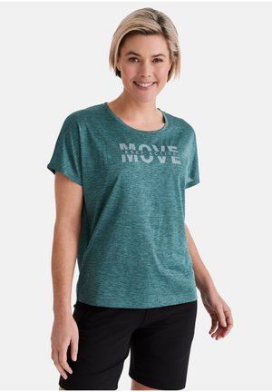 Lächelnde Frau mit kurzen blonden Haaren trägt ein türkisfarbenes T-Shirt mit dem Text "KEEP ACTIVE MOVE" und schwarze Shorts, steht vor weißem Hintergrund.