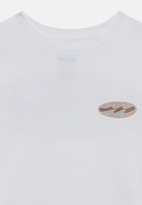 T-shirt bianco in cotone con un piccolo logo ovale in teal e marrone all'altezza del petto, dotato di collo girocollo classico e texture liscia.