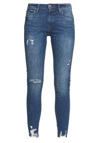 Vaqueros ajustados de algodón, con un acabado desgastado que presenta rotos en las rodillas y en el dobladillo, exhibiendo un diseño clásico de cinco bolsillos.