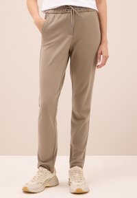 Beiga joggers i mjukt tyg, med elastisk midja och snörning, sidofickor och slim-fit design.