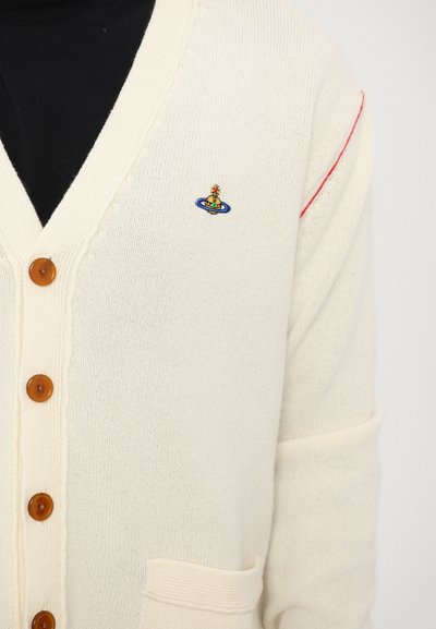 Cremefarvet cardigan med træknapper, V-halsdesign og et broderet planetlogo på brystet. Blød strikket tekstur med røde detaljer.
