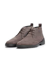Botines de ante gris con una textura suave, que cuentan con un diseño de cordones, una punta redondeada y una suela de goma negra contrastante.
