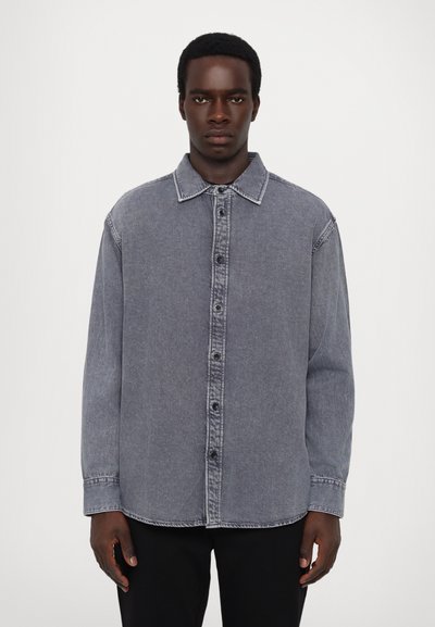 Denim shirt in faded gray with a button-up front, pointed collar, and long sleeves; features visible stitching and a relaxed fit.