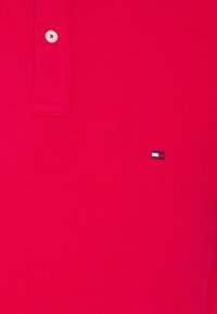 Rotes Polohemd aus einer strukturierten Baumwollmischung, mit einer Drei-Knopf-Leiste und einem kleinen gestickten Logo in Blau, Weiß und Rot.