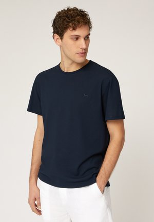 T-shirt in cotone blu navy con collo tondo e maniche corte, caratterizzato da un discreto dettaglio logo sul petto. Texture liscia.